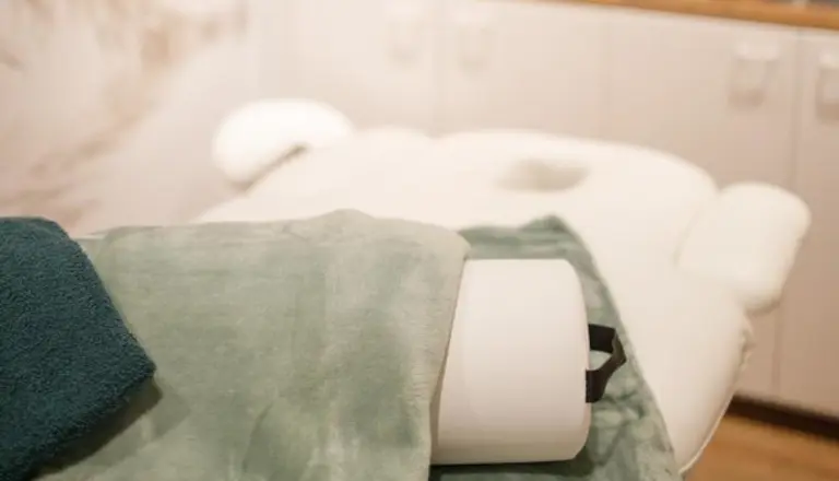 Groene handdoek op een massagetafel in onze massagesalon, klaar voor een Chinese hoofd-, nek- en schoudermassage